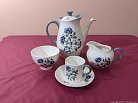 Full coffee set displayed on table including coffee pot, sugar bowl, cream jug, one cup and one saucer