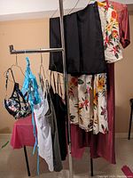 Eight pieces of women's clothing hanging on a rack including bikinis, camisoles, skorts, and a long robe.