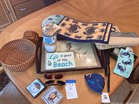 Overview of most lot contents including lazy Susan, table runners, placemats, sunglasses, game, candles, wall plaque, trays and basket