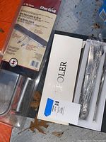 LPoler flatware set in white sealed box placed beside Char-Broil bar burner packaging.