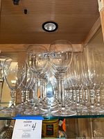 Shelf with several clear crystal glassware types including long stemmed wine glasses and short stemmed glasses