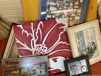 Displays all six items including framed wine bottles print, red floral stretch canvas, framed bicycle print, coastal landscape paintings, and a wooden beach sign.