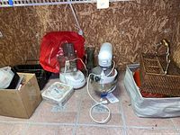 Overview of all items in the lot including KitchenAid mixer, Cuisinart food processor, glass vase, wicker basket, roasting pan, and plastic containers.