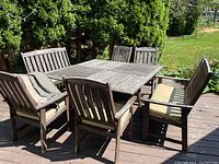 Wide shot of solid wood outdoor table and six chairs on deck, with cushions on all seating