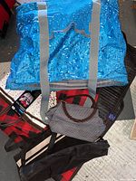 Large blue insulated tote, front view showing water drop pattern and gray handles, with other totes and blanket around