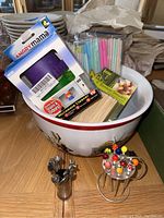 Overhead photo showcasing Warner Bros bowl filled with Angry Mama microwave cleaner box, bamboo skewers, plastic straws, and metal appetizer skewers in front