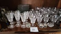 Crystal stemmed glasses and small lidded containers on wooden shelf
