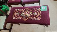 Top view of burgundy embroidered floral needlepoint upholstery on bench seat