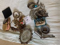 Overview of mixed jewelry and serving pieces on blanket