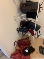 Seven leather purses arranged on wire shelves and floor corner, various colors and styles visible.