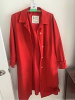 Red London Fog coat medium/large size hung on a door, showing front and sleeve details.