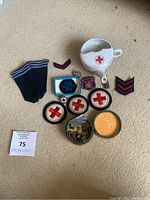 Top view of military RN/DR items including patches, socks, and ceramic cup with red cross