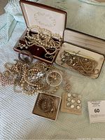 Overview of multiple pearl and faux pearl jewelry pieces including necklaces, earrings, bracelets, and display boxes on a fabric surface.