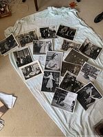 Overview of all 14 black and white photographs laid out on a cloth on the floor showing various historical figures including Queen Elizabeth II and Winston Churchill.