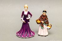 Front and side views of two Royal Doulton porcelain figurines on a neutral background showing details of dress and baskets.