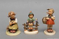 Front view of three Goebel figurines showing detailed expressions and poses