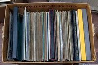 Box filled with a large number of vinyl records packed vertically, showing album spines and covers.