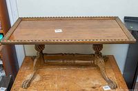 Full frontal view of the entire coffee table showing the rectangular top with nailhead trim around the edge and carved claw feet base.