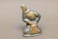 Front angled view of the vintage Inuit soapstone carving showing figure in traditional attire with green and brown tones.