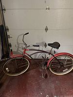 Full side view of the vintage men's Murray Monterey bike showing red frame, whitewall tires, black seat, and swept chrome handlebars.