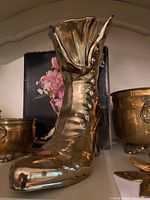 Close-up of brass boot-shaped vase showing details and patina