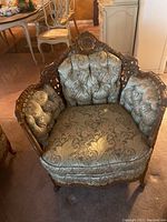 Front view of accent chair showing tufted fabric seat and back with carved wood frame.