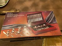 Box labeled '65 Piece Olde Bouquet Silver Plated Flatware Service for 12' with image of flatware set shown on top.