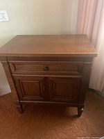 Front view of vintage wooden nightstand showing drawer and cabinet doors.