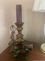 Photo showing the candleholder with purple candle and metal jewelry holder with figure base