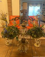 Full view of the three-piece candleholder set with central ornate candleholder featuring hanging crystal prisms and two glass bowls containing vintage faux floral arrangements on gold bases.