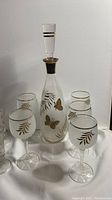 Image showing frosted glass decanter with gold hand-painted butterfly and leaf design along with 5 matching wine glasses with gold leaf detail