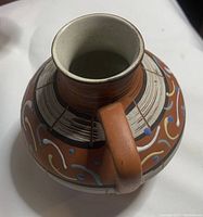 Top view showing vase opening, handle, and painted abstract decorations.