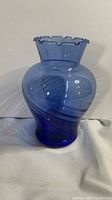 Front view of the light cobalt blue blown glass vase showing swirled pattern and scalloped top