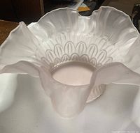 Top view of pink frosted glass candy dish showing flared ruffled edges and fish scale pattern on sides.