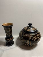 Photo showing both carved wooden items side by side: round lidded container and tall vase with carved bird and floral designs on black lacquer.