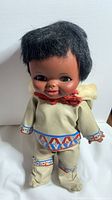 Front view of the vintage Inuit Reliable doll showing the facial details and part of the traditional outfit with decorative trim and fur collar.