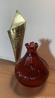 Red ribbed glass vase and brass wall pocket shown together from front angle.