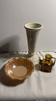 Photo showing the Roseville vase, bowl, and amber glass vinegar bottle grouped together on a white surface.