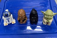 Front view of the four Star Wars character flashlights placed on a blue surface showing their detailed designs.