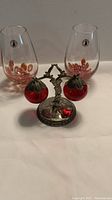 Pair of vintage glasses with red floral bubble designs and a metal apple shaker stand with two red apple-shaped shakers.