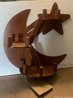 Front view of the wooden wall shelf showing crescent moon and star shapes with two platforms connected by wooden ladders.