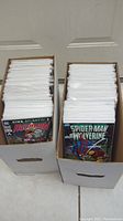 Two long-boxes of comics showing Aquaman #2 and Spider-Man/Wolverine cover issues in protective sleeves.