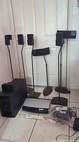 Full setup of Bose home theater system components including satellite speakers on stands, subwoofer, main console, remote, and wires.