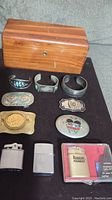 Full lot overview showing miniature Lane cedar chest, 4 belt buckles, 3 bracelets, and 3 lighters.