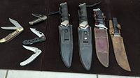 All knives displayed including fixed blades and folding knives on dark surface