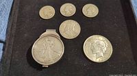 Seven silver coins displayed in a black box including a money clip with a 2007 American Eagle coin attached, plus Peace Dollar, Franklin half dollar, and three quarters.