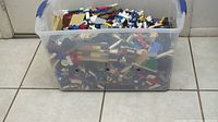 Plastic tote filled with assorted LEGO bricks and parts of various colors and shapes.