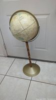 Full view showing globe mounted on wooden stand with metal base, illustrating overall condition and structure.
