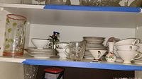 Shelf displaying Bavaria China teacups, saucers, plates, clear glass pitchers, and vases.