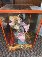 Full view of the Vintage Japanese Geisha Doll in glass display case with orange frame, showing the doll's outfit, pose, and decorative base inside the case. Visible crack on the glass noted.